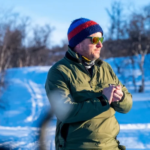 Man stood on snow and surrounded by sparse, bare trees