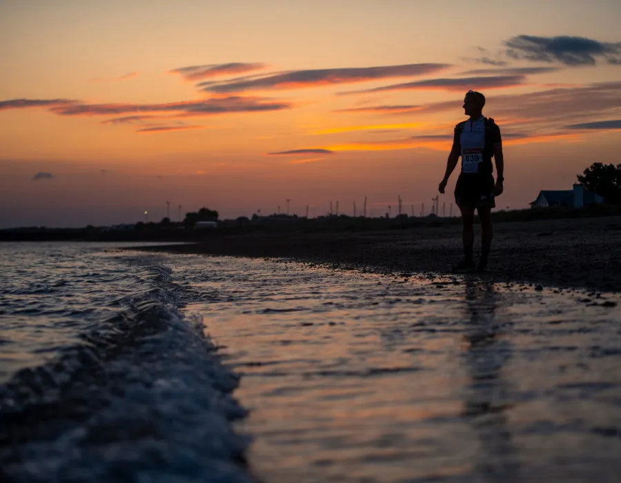 Man stood at coast with sunset behind him