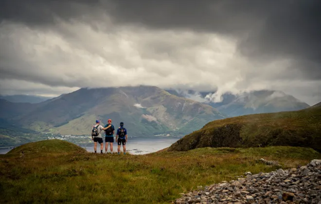 Three people stood, looking out at water below